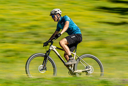 Pyöräilijä, jolla on sininen t-paita ja kypärä, Cube Reaction -maastopyörän hardtail-pyörällä.